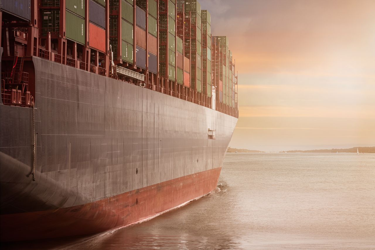 Crafting Captivating Headlines: Your awesome post title goes here A colossal cargo ship loaded with containers navigates through calm waters against a vibrant sunset sky.